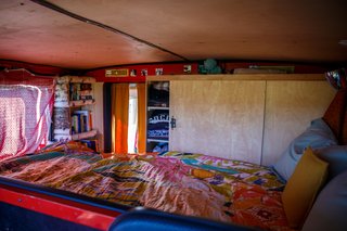 The couple sleep in a lofted bed with storage directly adjacent.