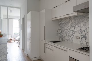 Integrated appliances now keep the area simple, modern, and efficient, and the narrow counter runs along the hallway to provide extra space for storage.