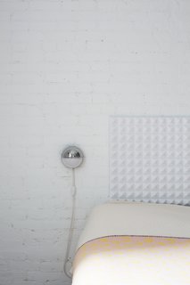 The headboard and brick wall provide much-needed texture and depth in the bedroom.