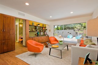 The den has a wall of custom wood cabinetry with original midcentury hardware.