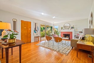 The large, open living room has oversized windows looking out onto the front porch.