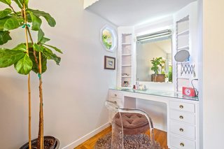 A built-in, sit down vanity that could also be used as a desk is located in a corner of the bedroom.