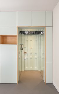 Mirrors line the entryway and short corridor to reflect light in this space, which has no windows. The floors are covered in linoleum throughout.