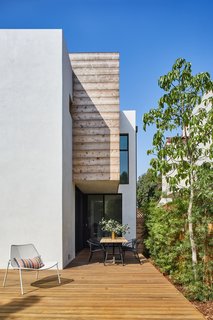 At the rear, a large open patio with wood planks and an outdoor eating space allow for indoor-outdoor living.