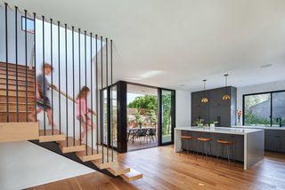The staircase is made from wood and metal, tying together other simple materials found throughout the home. The white oak is echoed by the flooring of the ground floor, while the black oxide finish reflects the dark bronze finish of the doors and windows.