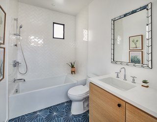 One of the bathrooms on the second floor contrasts crisp white tile on the walls with geometric blue tile on the floor.
