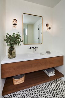 A white and wood bathroom is complemented by patterned geometric tile and a simple metal mirror.