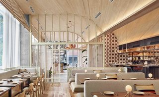 The interiors of ATX Cocina in Austin feature lots of wood, neutral tones with pops of color, and a vaulted ceiling to create a sense of enclosure.