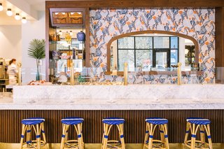 Textured wood walls and bar, bold textiles, and moody paint colors create a modern French vibe in Austin's Le Politique restaurant.