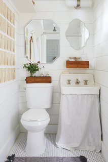 In search of a home office for designer Paige Morse, she looked to two existing sheds in her own backyard and transformed them into a workspace complete with a small bathroom. The walls, floor, and tile floor are all white, including a vintage white sink.
