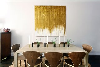 At an apartment in Brookyln, AphroChic designers Jeanine Hays and Bryan Mason played with different tones of wood and metal in the dining area to achieve a space that is both modern and elegant; the light gray color of the walls keeps the space from feeling too sterile, and provides a warm backdrop for the gold-and-white artwork.