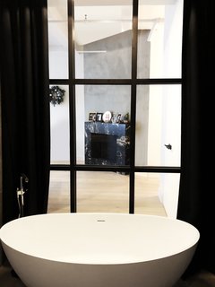 A bathroom designed Studio 397 Architecture peeks out into an adjacent room with a fireplace elegantly clad in a dark marble with a honed sheen.