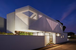 At night, the battens on the facade glow, further emphasizing the triangular shapes inspired by the gabled roofs of the home and its neighbors.