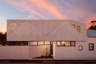 Inspired by the slopes and angles of the existing home’s gabled roof and those of the Victorian homes in the area, the design team created a faceted, angular facade of vertical battens for the new extension.