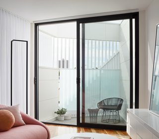 A small terrace on the second floor is partially enclosed with battens and polycarbonate for privacy, but the spacing of the battens and the translucency of the polycarbonate still allow for light and views of the city beyond.