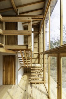 The staircase at the rear of the home climbs up along the glass facade, allowing for elevated views of the forest.