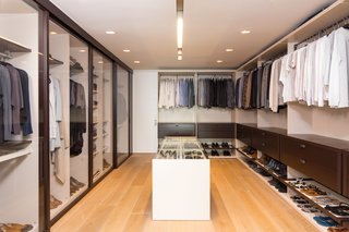 10 Modern Walk-In Closets - Photo 5 of 10 - In this example, clean lines and warm textures create a thoroughly modern design. Glass doors open up the space and extend the open-floor plan.