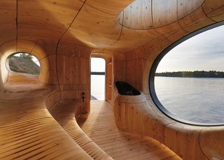 The space is lined with CNC-cut wooden panelling that creates a sinuous interior encompassing traditional stepped sauna seating and biomorphic-shaped porthole windows.