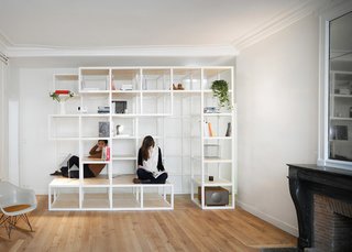 In the living room, modular wooden shelves and cabinets create areas that can be used as bookcases, seating, or as a climbing frame.
