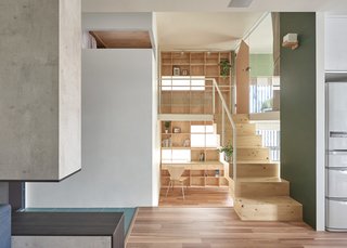  Behind the blocky staircase, a double-story bookcase covers the entire wall behind with shelves, windows, and even a desk. 