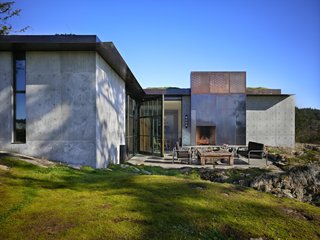 Throughout the house, the rock extrudes into the space, contrasting with the luxurious textures of the furnishings. Interior and exterior fireplace hearths are carved out of existing stone; leveled on top, they are otherwise left raw. A large pivoting steel and glass door opens for access to an outdoor terrace.