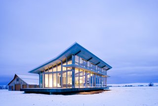 10 Modern Glass Homes - Photo 7 of 10 - Surrounded by wheat fields on a high-altitude plateau stands a small glass house and a solid, traditional barn. The owners, inspired by Philip Johnson’s Glass House, wanted a refuge that opens up to the prairie and mountains.
