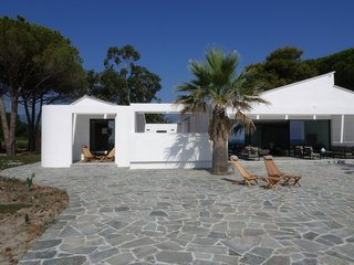 10 Modernist Beach Home Rentals to Escape to This Summer - Photo 10 of 10 - Located steps from the beaches of Corsica, this striking modern beach house was designed by Paris-based architect Vincent Leprince, as a bright and bold reference to the sunshine-washed coastal surroundings. It features living room doors that open onto a terrace with panoramic views, and that leads directly to the beach. The home is tastefully decorated with contemporary furnishings and includes a heated spa with views of the island of Monte Cristo. 