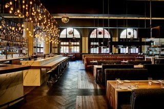 Guests are greeted by plush leather booths and classic hardwood floors in the chic bar area.