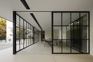 50 Modern Homes With Floor-to-Ceiling Windows - Photo 26 of 50 - In their approach to renovating and adding an extension to Hopetoun Road Residence, B.E. Architecture sought to first "retain the existing structure as an anchoring element." To do that, the architects clad the gabled facades in the front and back with polished grey render, then wrapped the entire original building with a floating roofline edged in copper. Underneath that, they tucked a series of glass pavilions with retracting walls, which allow the new interior spaces to merge with a pool and terrace.