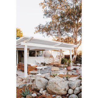 This pergola-covered seating area—featuring hanging chairs—is off the living room.