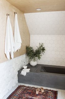 In the bathroom, 6" hexagon tiles from Fireclay line the wall above the tub, which is Kohler's Underscore Vibracoustic Bathtub surrounded by a custom frame finished with polished concrete.