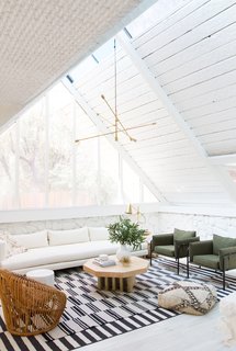 In the living room, Samuel painted the exposed wood and stonework to unify the space and let the original texture step forward. (The wood had been painted already by previous owners.) A custom ten-foot sofa sits below the window and the green canvas armchairs are from Urban Outfitters.