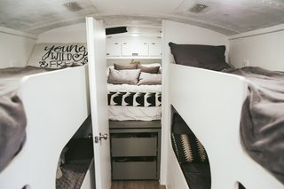 There are four bunks for the kids' sleeping area, fitted over the wheel wells, and a door that separates the parents' bedroom at the back of the bus. Because the mattress is positioned over the engine, it sits high enough so there can be clothing storage below it. The couple writes on their blog: "Our bedroom has so much storage we haven't even used all of it!"