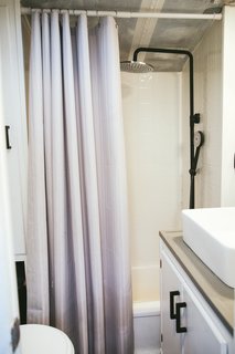 The matte black hardware and shower fixture is consistent with the kitchen finishes.