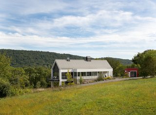 The exterior form and materials of the house echo historic farmhouses in the area, while the garage, clad in red board and batten, evokes old barns. Wiedemann reinterprets the function of a traditional cupola here, which was typically used to aid interior ventilation, by inserting a whole-house fan in this one.