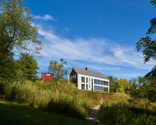 A view of the back side of the two-story home reveals its dramatic glazing, which provides both levels with far-flung views into the site.