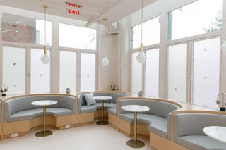 Another seating area houses curvy crescent booths and pedestal tables.