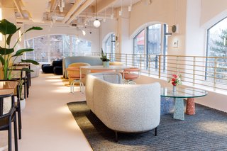 A glass-topped coffee table with colorful terrazzo legs is a playful contrast to a couch with curved sides.