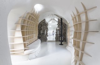 The design team writes, "As a wooden grid structure, the furniture pieces pull the structural grid through the surface of the GRP walls and seem to be peeling off the tube."