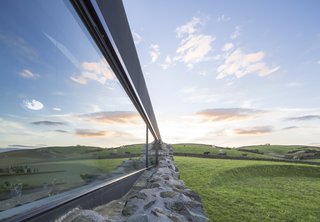 The long, rectangular window meets the stone wall.