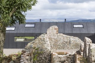 The building's modern exterior cladding contrasts dramatically with the existing ruins.