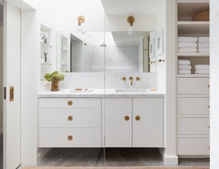 A 1957 Midcentury in Seattle Receives a Striking Makeover - Photo 9 of 16 - The Carrara marble counter and backsplash, concrete floors, frameless mirror, and white cabinets keep the look chic and consistent in the bathroom.