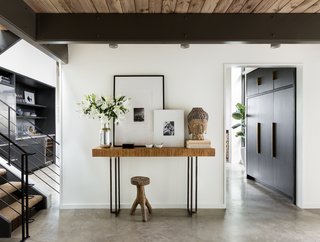 A 1957 Midcentury in Seattle Receives a Striking Makeover - Photo 2 of 16 - Starting with the front hall, the architects have opened up the enclosed stairwell and utilized a lighter palette to bounce natural light around. White walls, concrete floors, and minimal trim produce a streamlined backdrop.