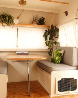 At the dinette, the bench bases were painted cream and given new upholstery in a light gray color. The couple kept the original table and had the top covered in strips of Cypress to match the new wooden floor.