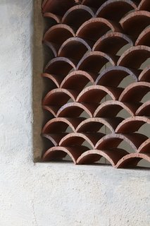 The architect created multiple decorative wall cut-outs throughout the home to facilitate ventilation, composed of roof tiles laid in a wave pattern.