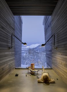 An "in-between" space creates protected circulation between the separate volumes. A sheet of glass frames the view outside. "The ceilings in these spaces are all made of oak slats that, through the treatment with iron sulfate, turn naturally black because of the high content of tannin," said Stinessen. "The airy and black ceilings retreat from the visual connection to the outside."