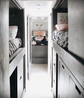 The kids' bunk area originally housed four bunks, but one was pulled out to create more storage. Two new sets of drawers and a closet can now hold the pantry, miscellaneous items, and the dirty clothes hamper. The drawer handle cut-outs double as footholds for climbing into the top bunks.