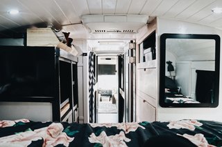 Looking back toward the front of the bus, more storage becomes visible. The pink dresser on the right holds the family's clothes. The gray dresser to the left incorporates a standing desk for Brandon and hides mechanicals.
