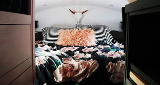 The couple were able to fit a king-sized bed in their sleeping area, where peachy-pink accents warm the interior charcoal and white scheme. "Our bed is the most comforting place I’ve ever been in," says Ashley. "It’s like an adult fort!" The mattress lifts up for easy access to electrical components and a 100-gallon water tank, along with extra towels, sheets, and winter coats.