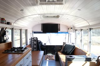 A look at the view toward the driver's seat and front of the bus. The family built two camel leather couches facing one another for the living area. A table can be placed between them for family meals. Built-in storage in the couch bases hold everything from extension cords and leveling blocks to board games and kettle balls. The armrests also open up and have outlets inside. "I intentionally built the five-inch ledge behind the couches for our coffee in the morning," says Ashley. "The kids also use this ledge to play with their LEGO mini figs or their tech decks. It serves its purpose well!"